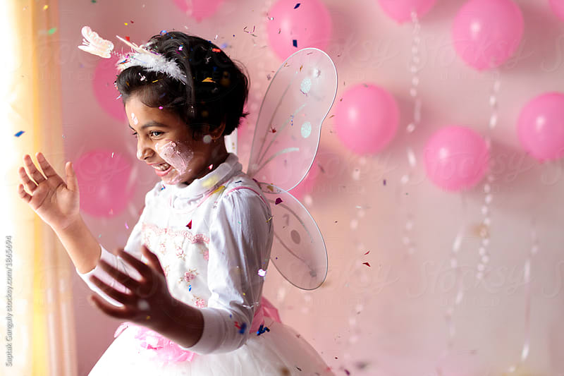 Cute little girl celebrating with confetti at her birthday party