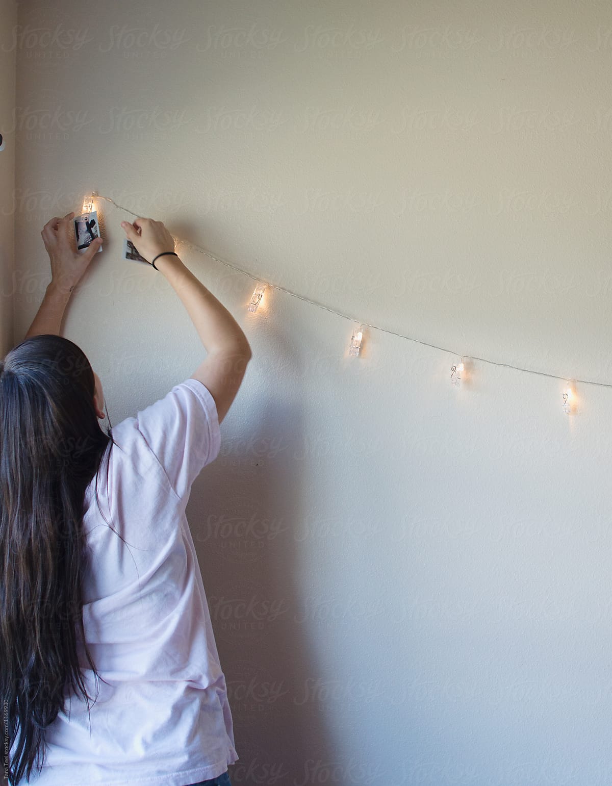 teenager hangs pictures on lighted string