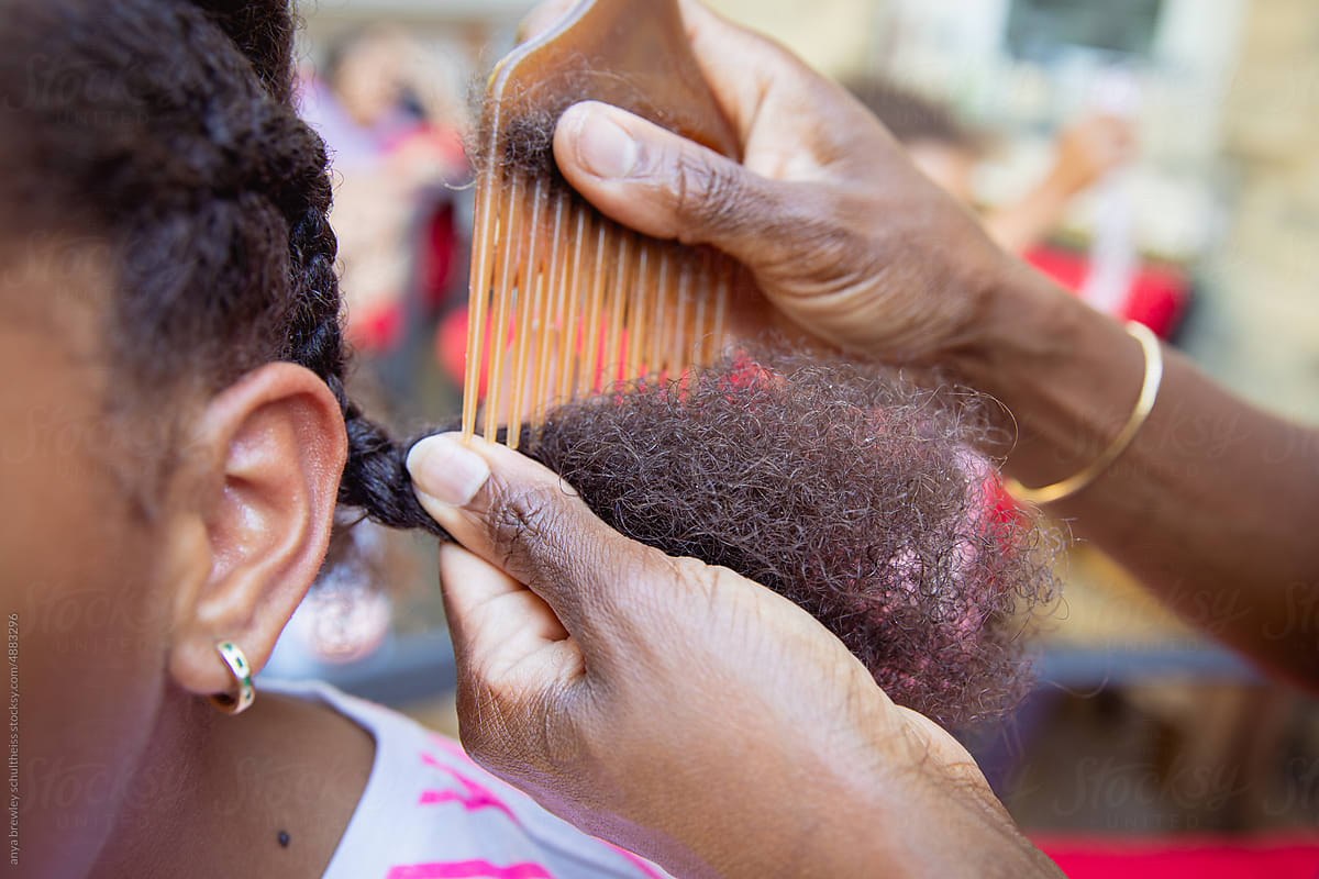Mother combing her child's kinky curly coily hair