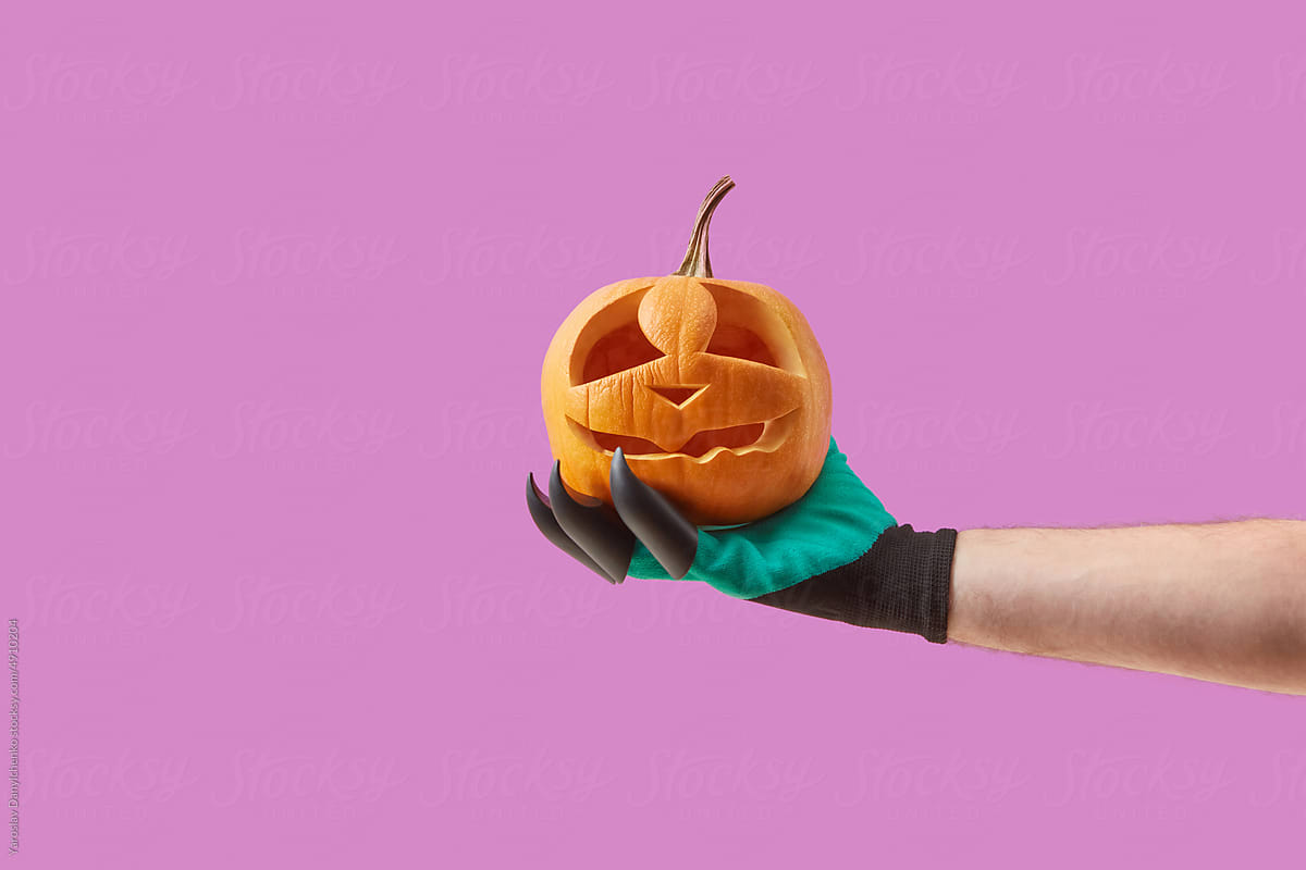 Jack-o-lantern in woman\'s hand in costume glove.
