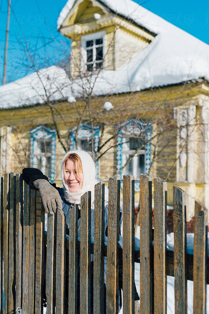 Smiling woman leaning on fence in winter
