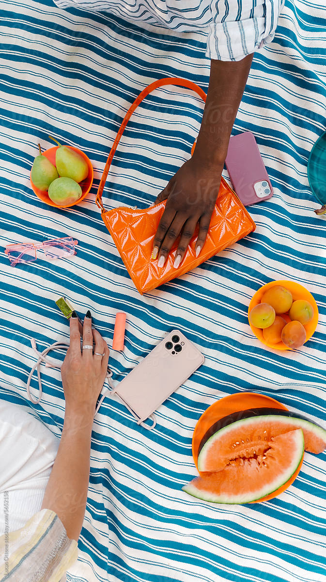 Hands of women reaching for random colorful in a picnic