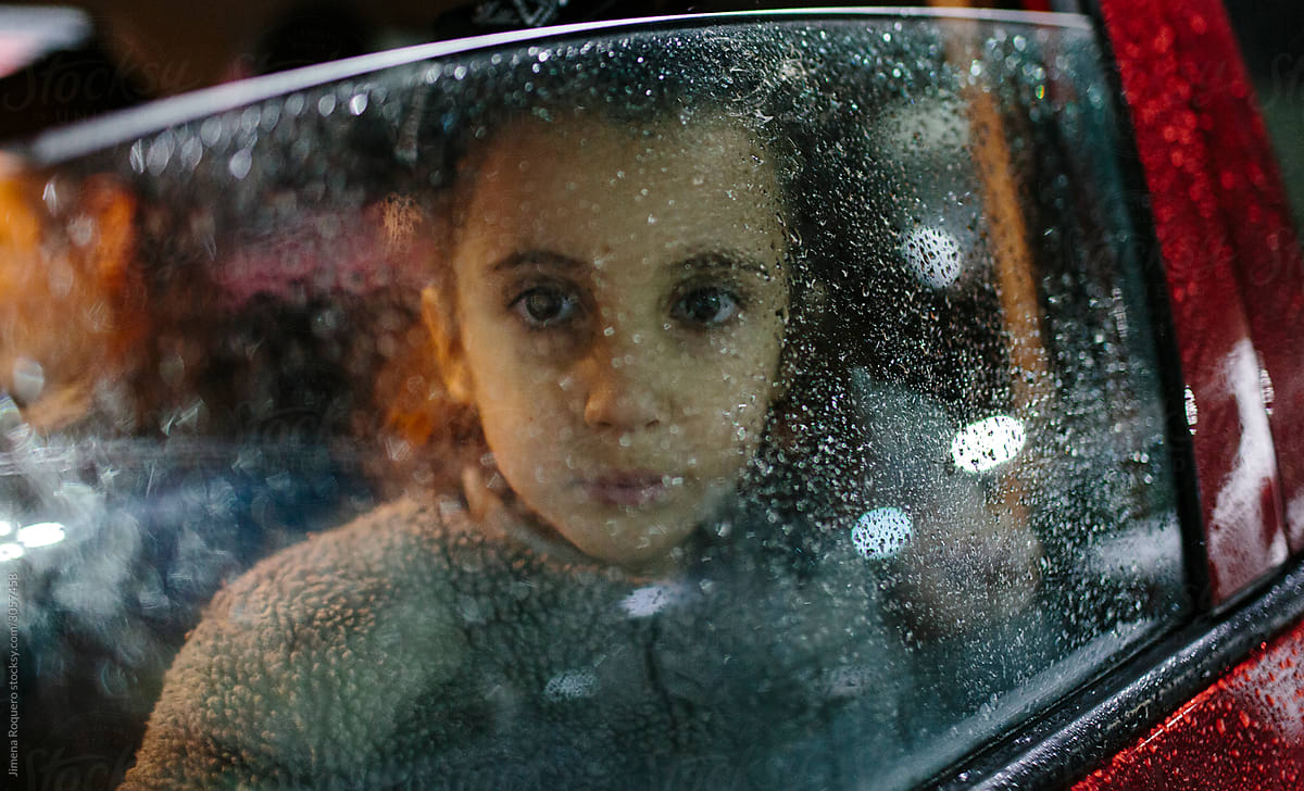 Little girl in the rain inside a car