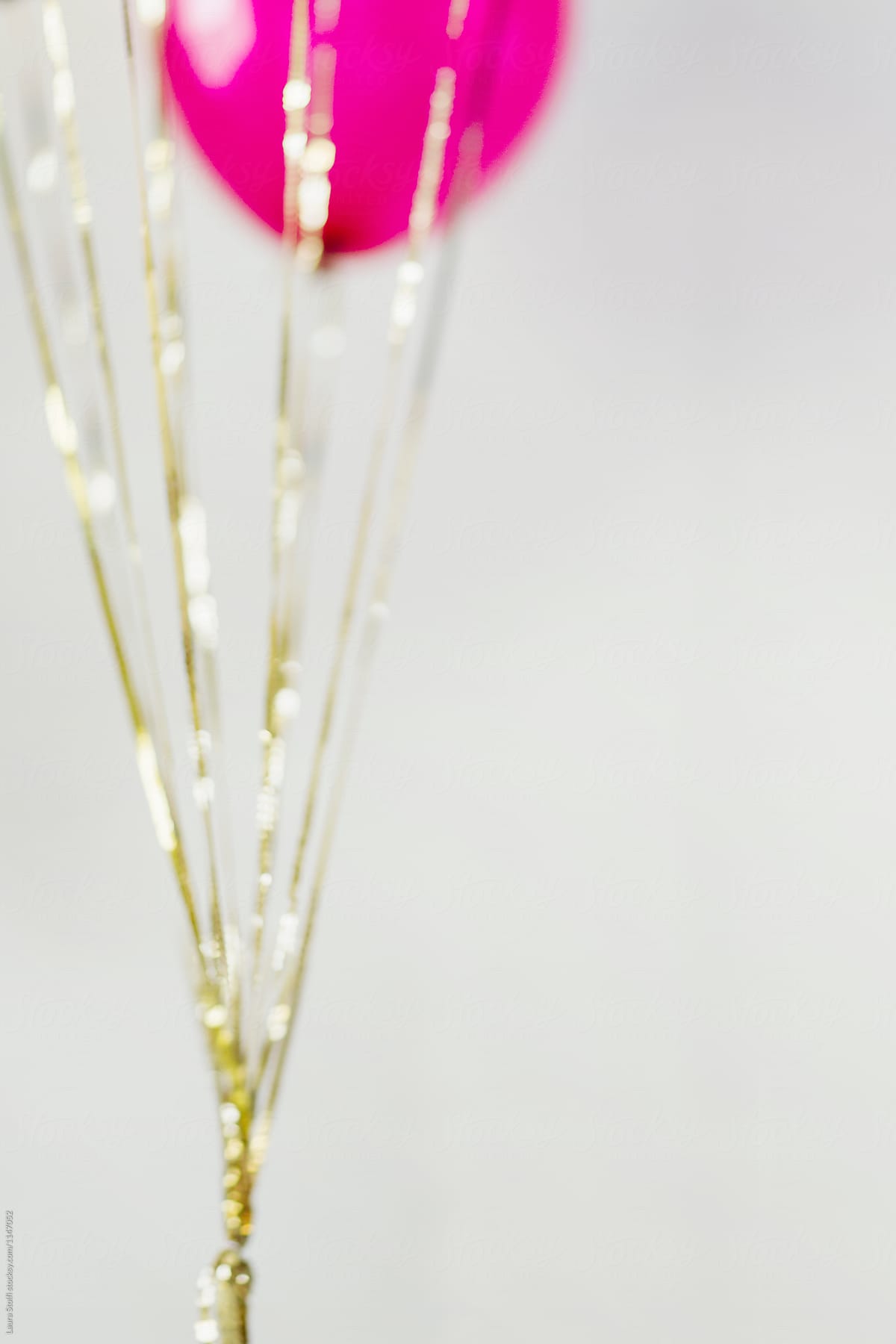 Blurry Gold Sequin Strings Hanging From Balloons by Stocksy