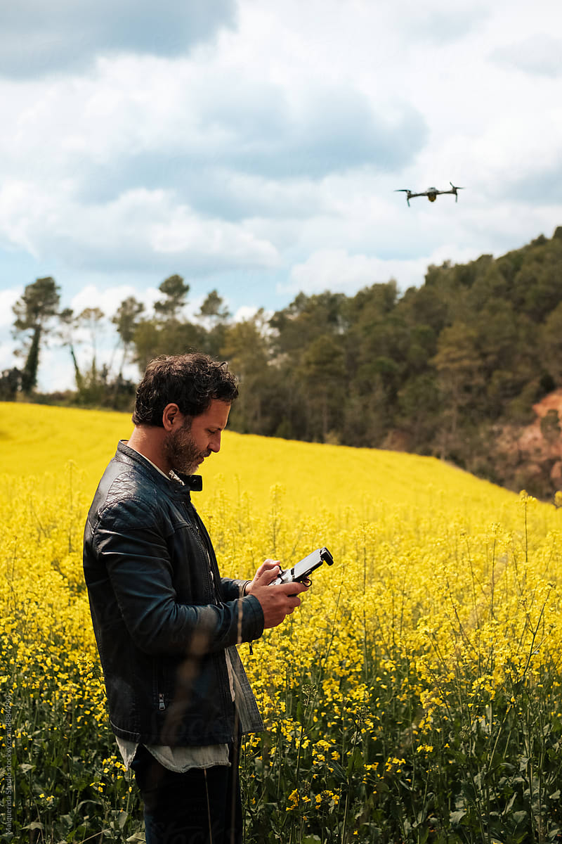 Man flying drone in a yellow flower field