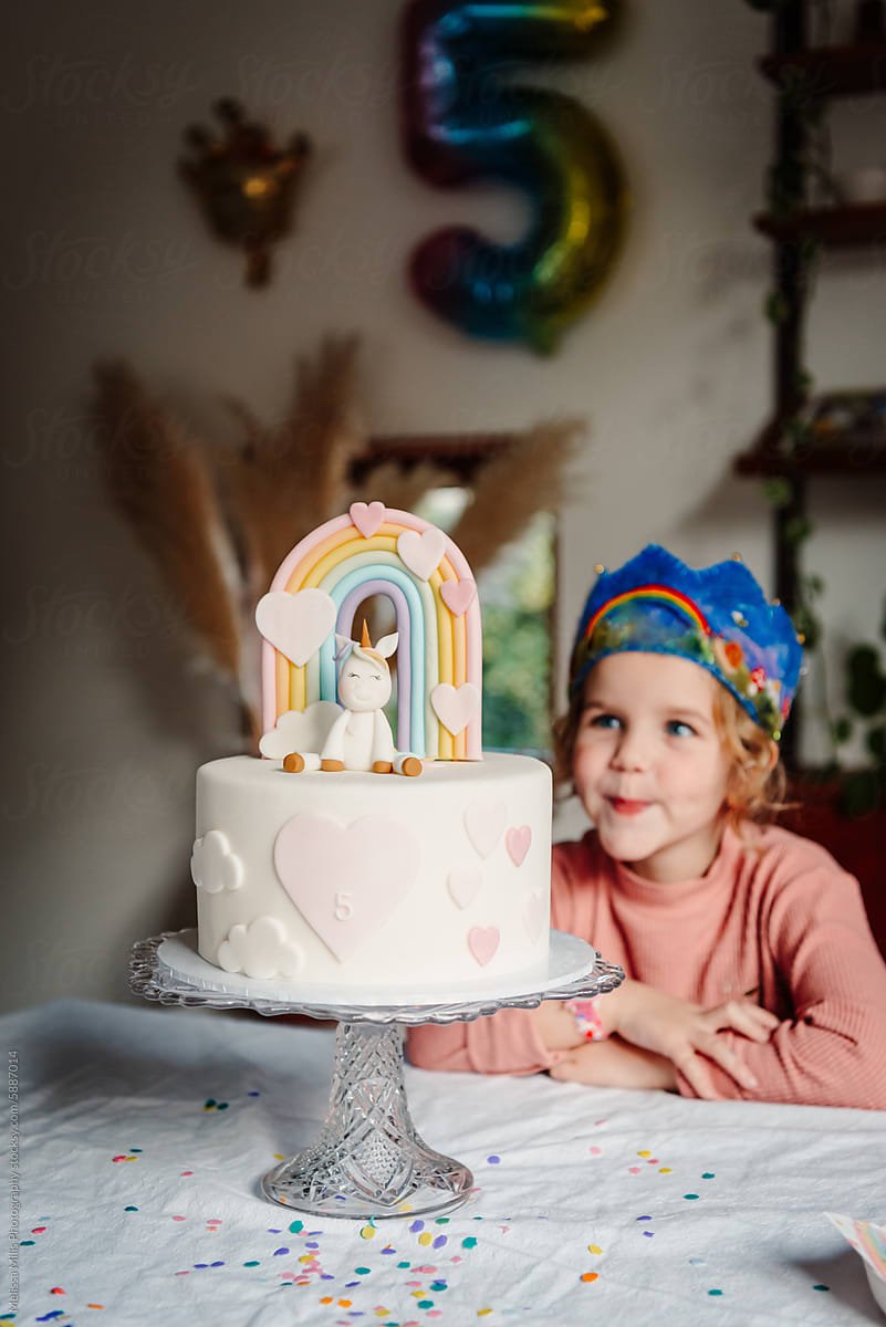Girl turning five with her unicorn and pastel rainbow themes bday cake
