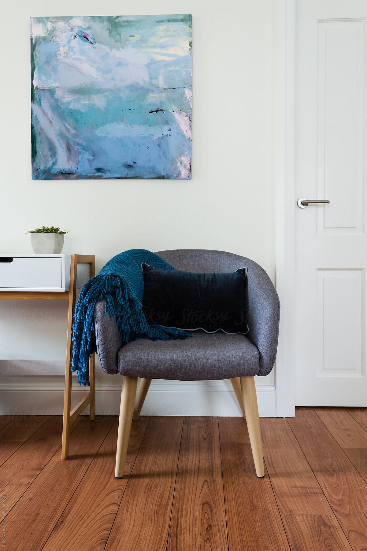 grey tub chair with rug and wall art