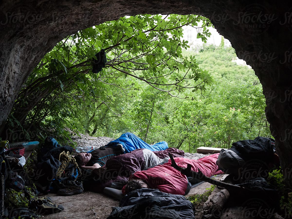 Group of friends sleeping under the rock in their sleeping bags