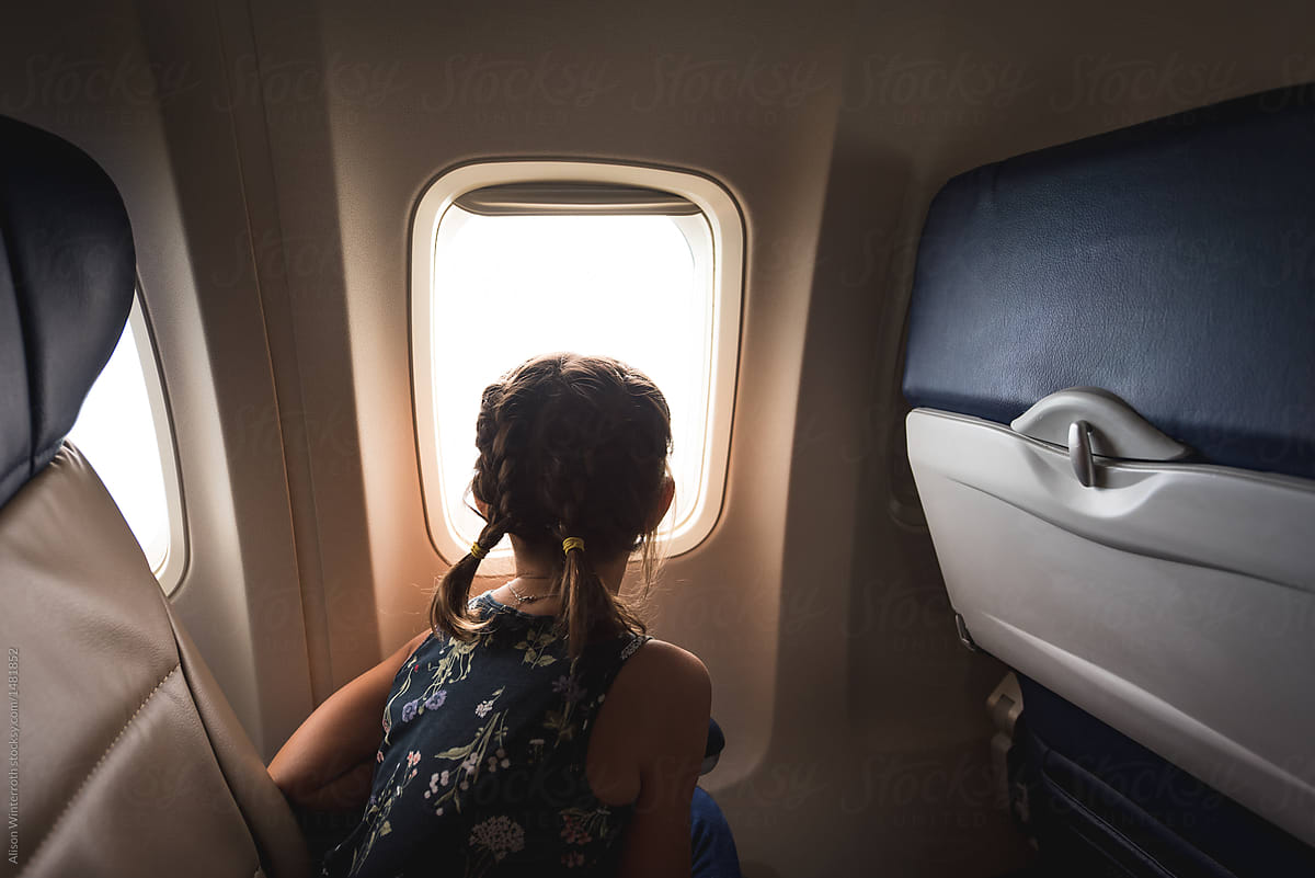 A Child Looking Out The Window Of An Airplane