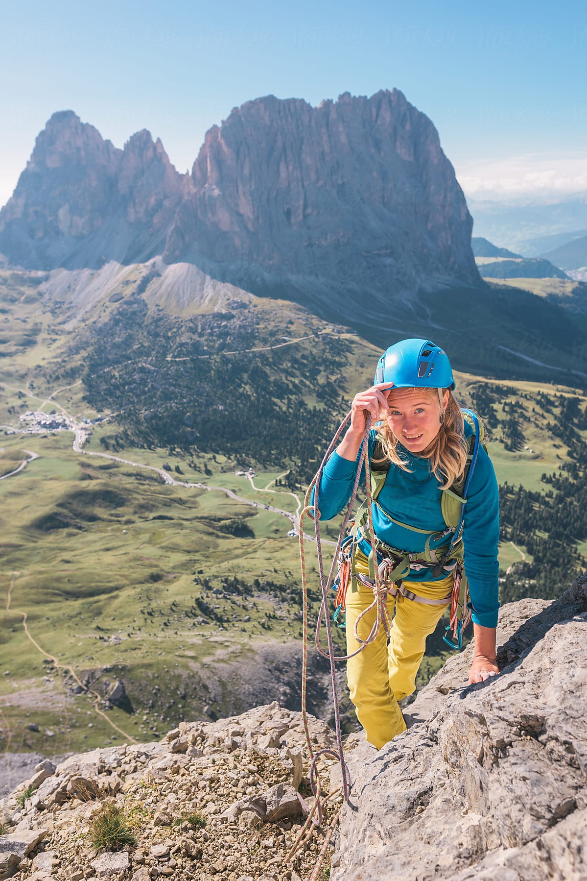 Beautiful female rock climber climbing mountains and smiling at camera