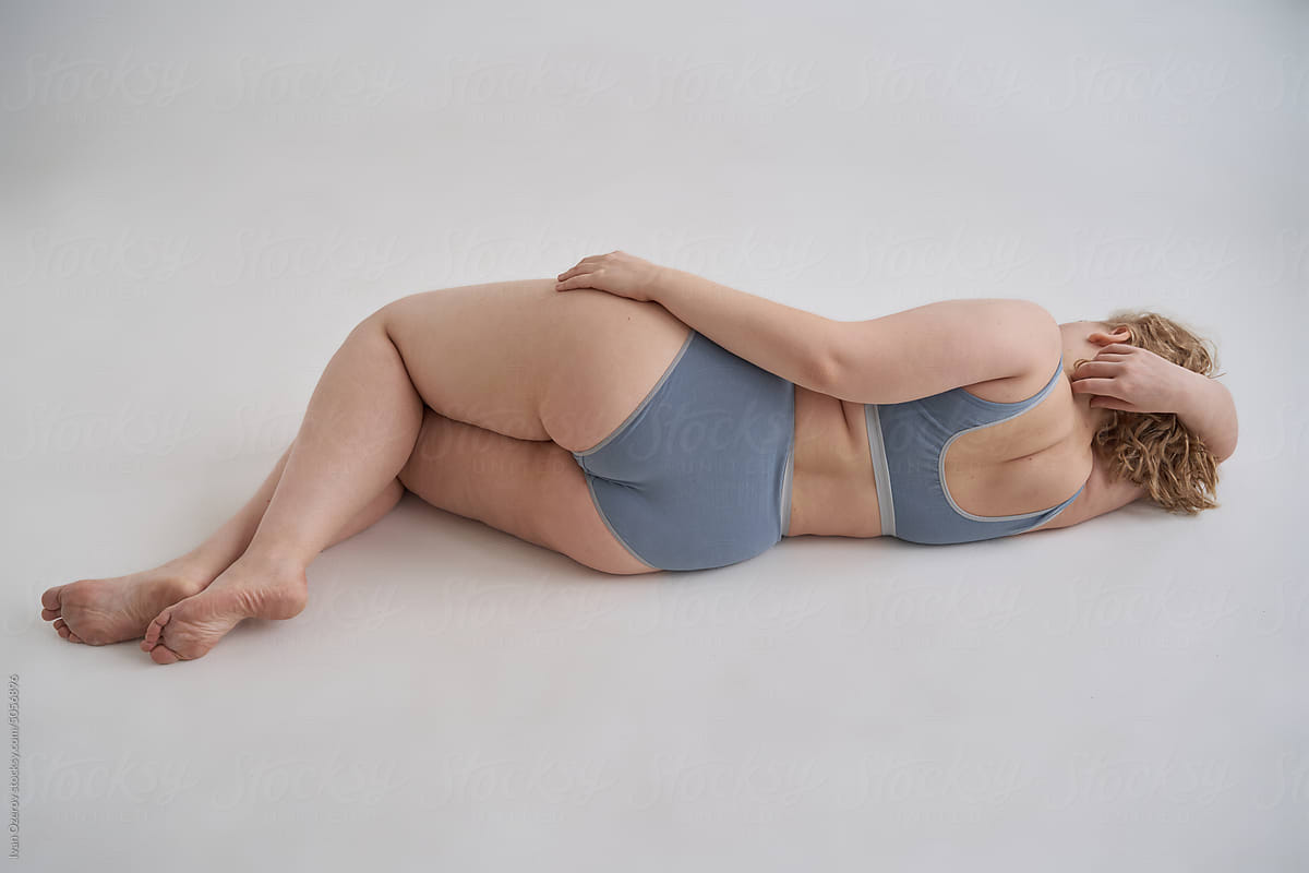 Anonymous plump woman lying against white background