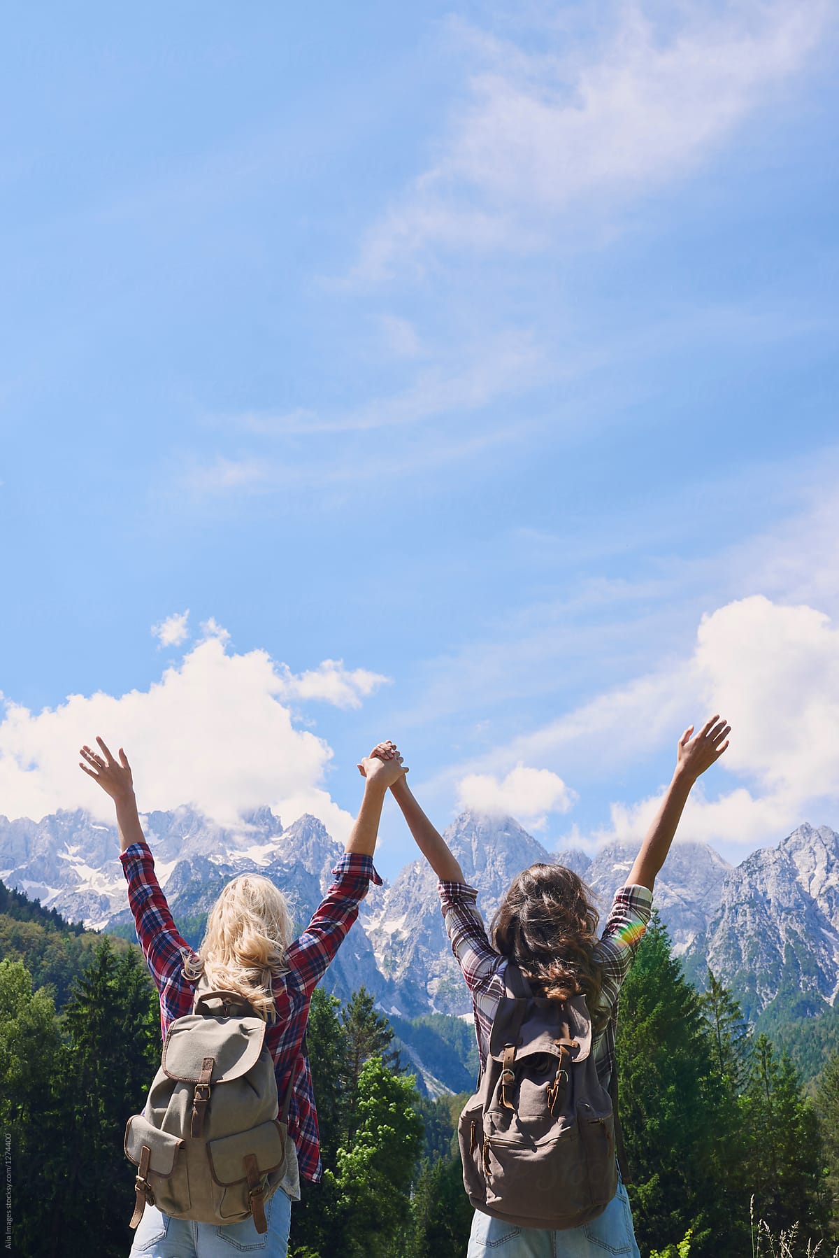 Travel girl friends celebrate adventure with arms outstretched