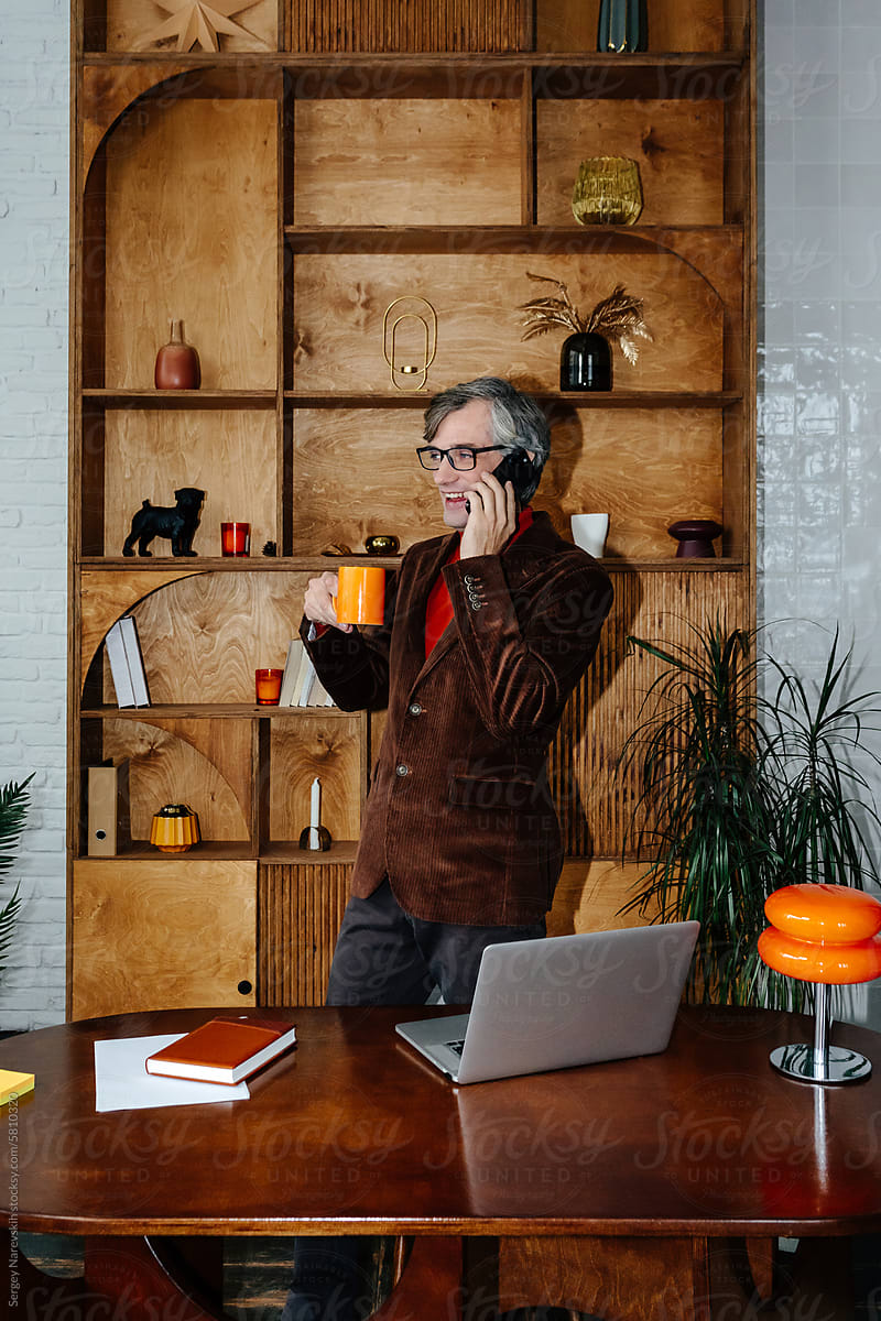 Businessman talking on phone holding coffee mug in office