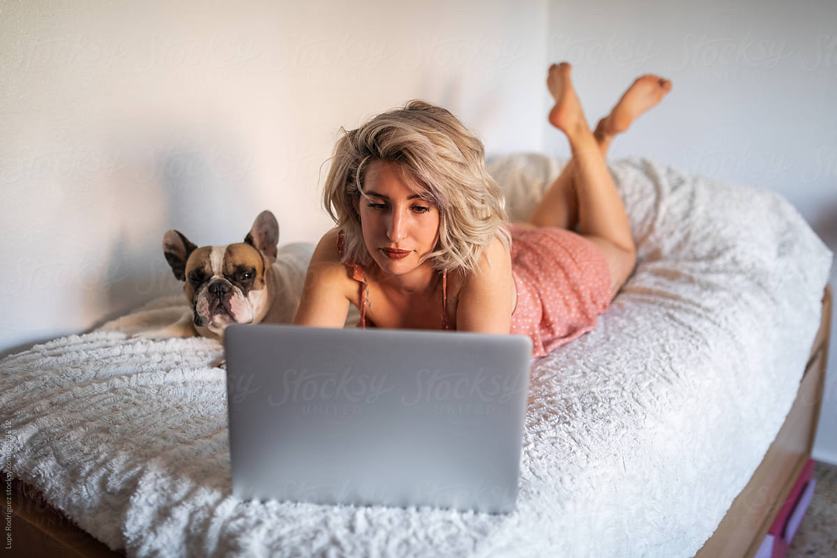 young woman at home with laptop next to her dog