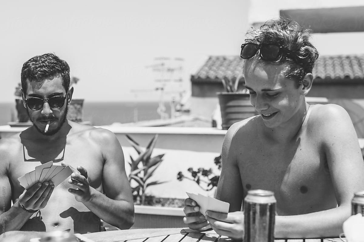two friends are playing cards, drinking beer, smoking and having fun
