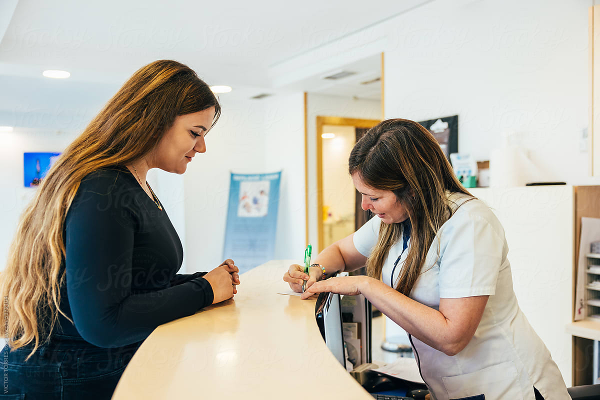 Nurse writing notes on paper near patient