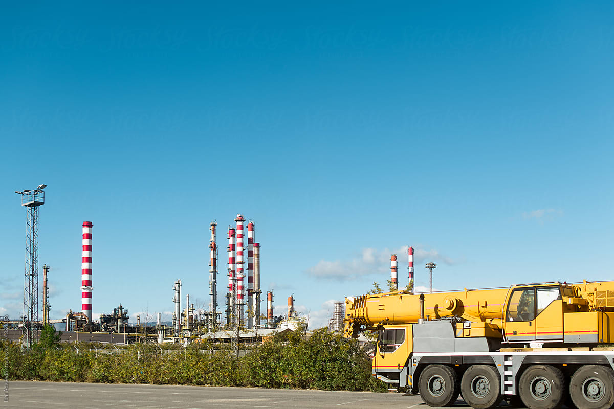 Heavy crane truck with refinery as background