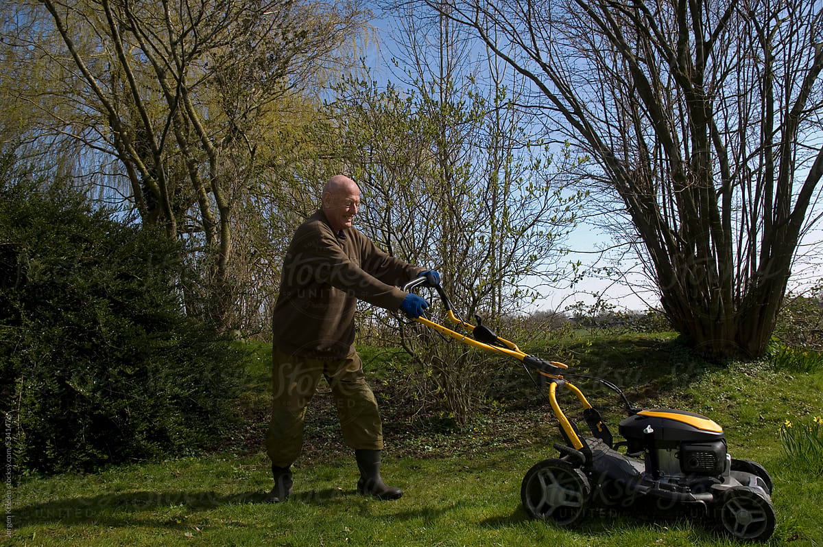 Elderly man mowing lawn