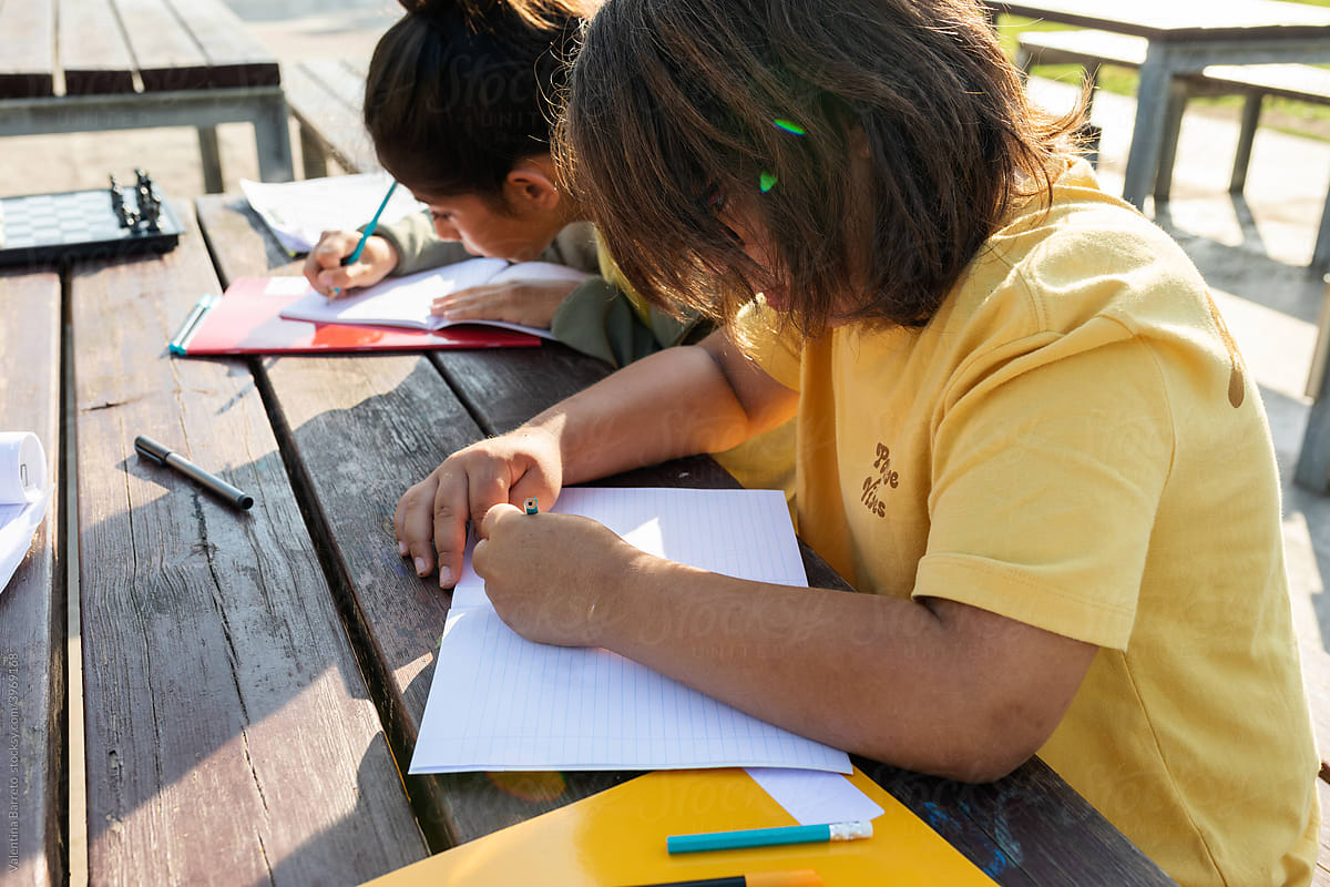 Kids doing homework at picnic table outdoor