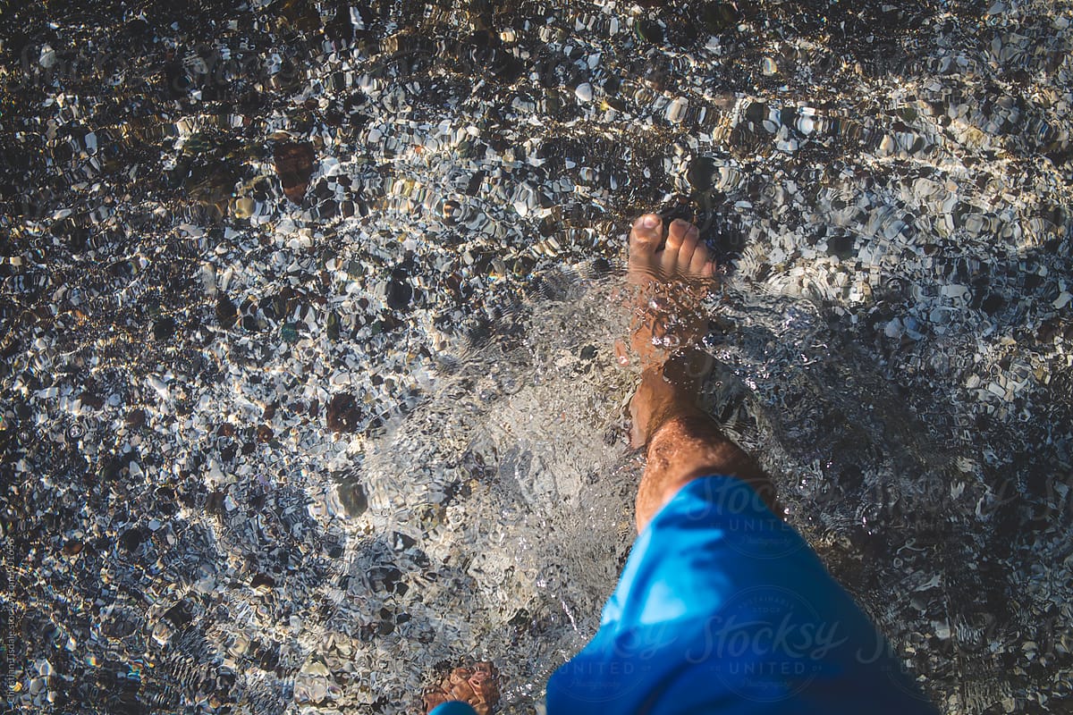 Bare foot walking in crystal clear water in the summer