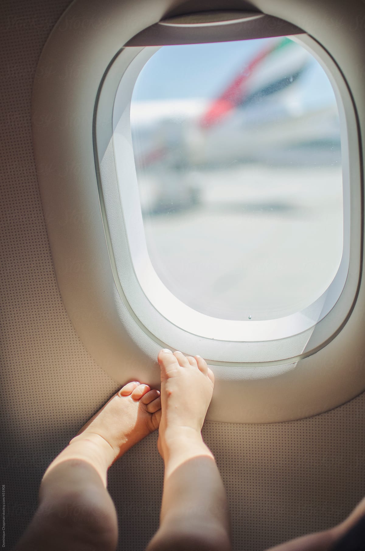Small childs feet next to plane window