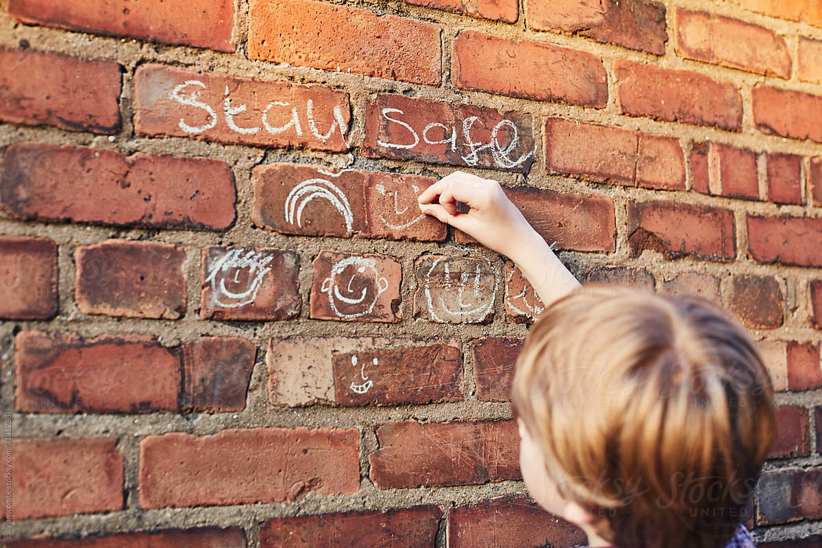 Child drawing with chalk on a brick wall