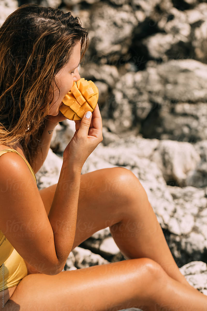 Woman Eating Mango at Beach
