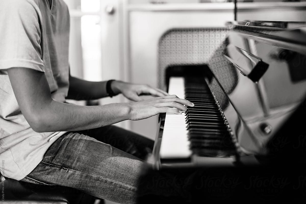 Black and white body shot of a teenage boy playing the piano