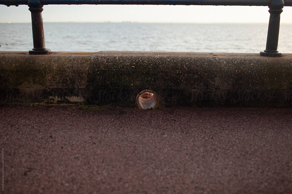 Girl\'s face seen through a hole in a coastal wall
