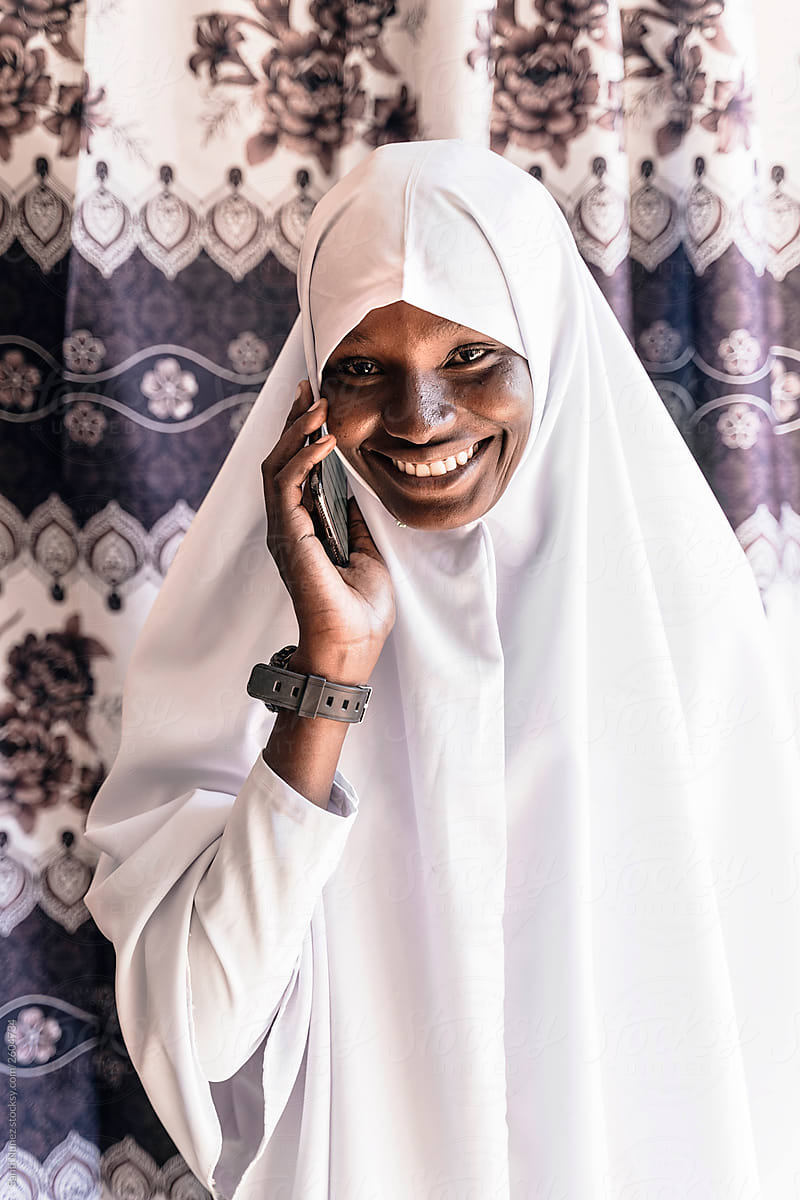 Young African Muslim wearing a white hijab using her mobile phon