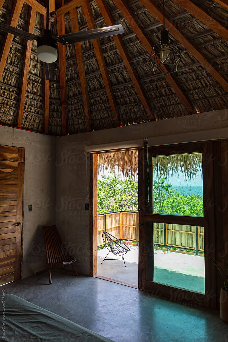 View from inside a room of a house with a high palm tree roof