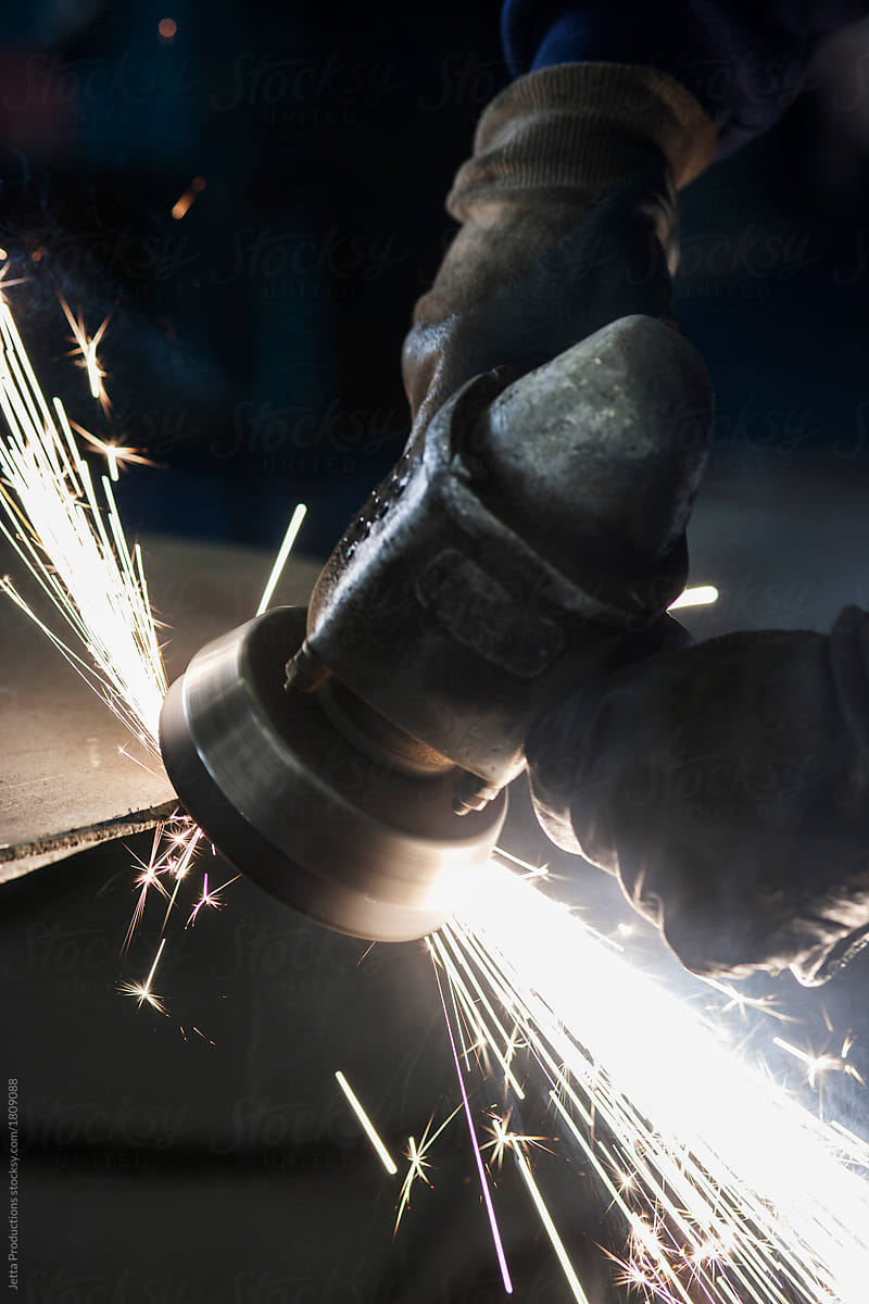 Male factory worker grinding on metal