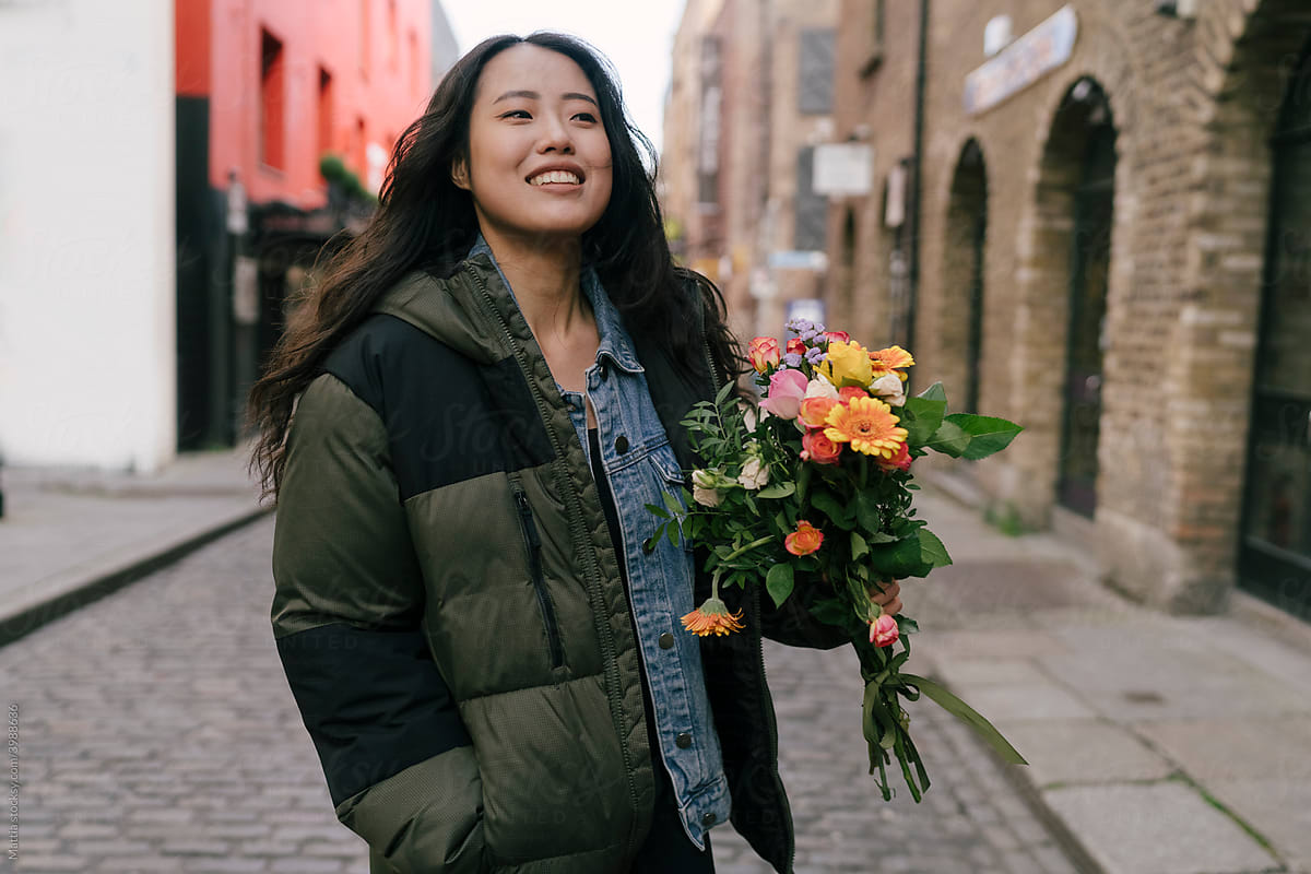 Happy Asian Woman Crossing the Street with Flowers