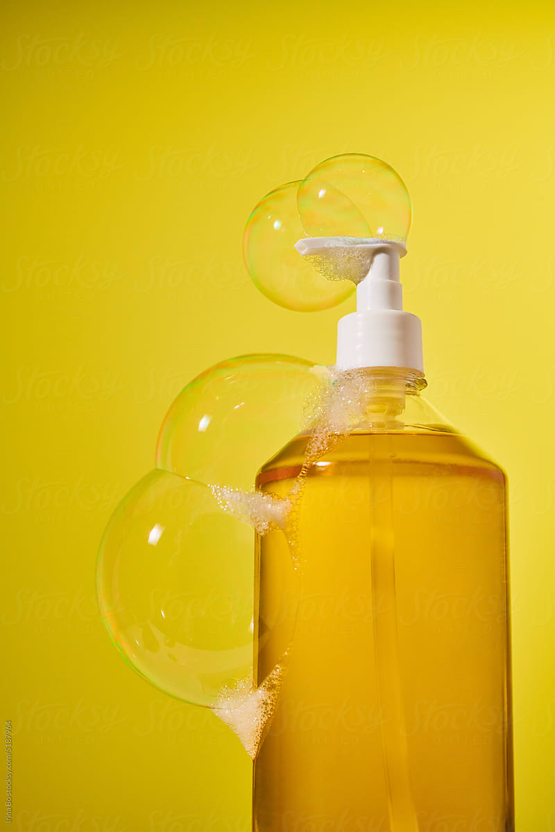 Bottle of liquid yellow soap in soap bubbles