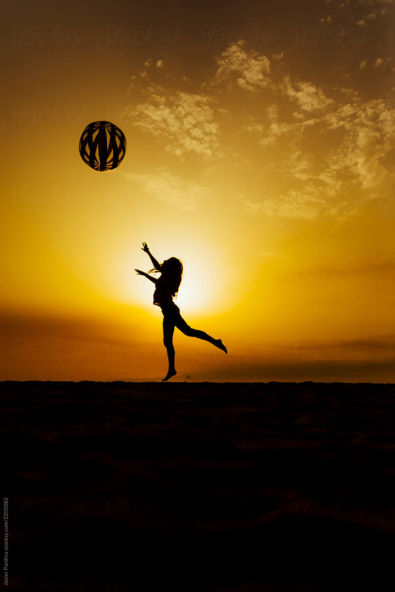 Silhouette of a woman playing with a ball
