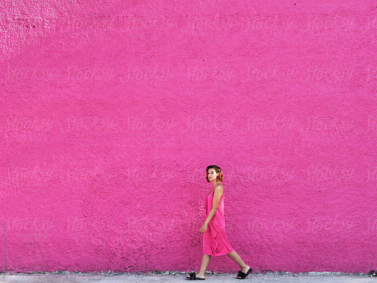 Walking girl in pink dress on street.