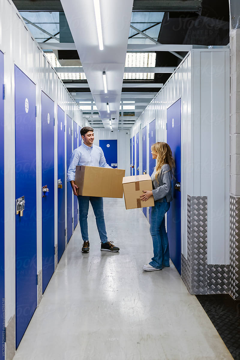 Young couple with carton boxes in storage room corridor