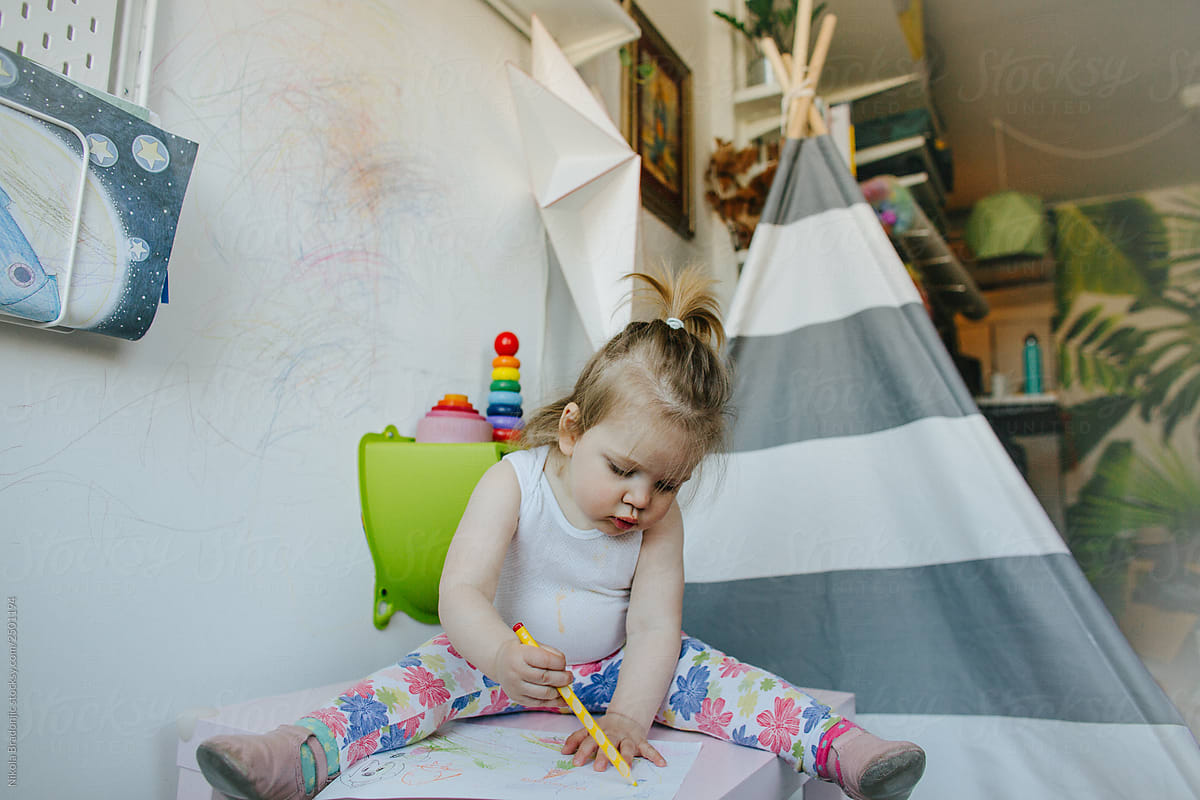 Cute toddler girl painting and writing