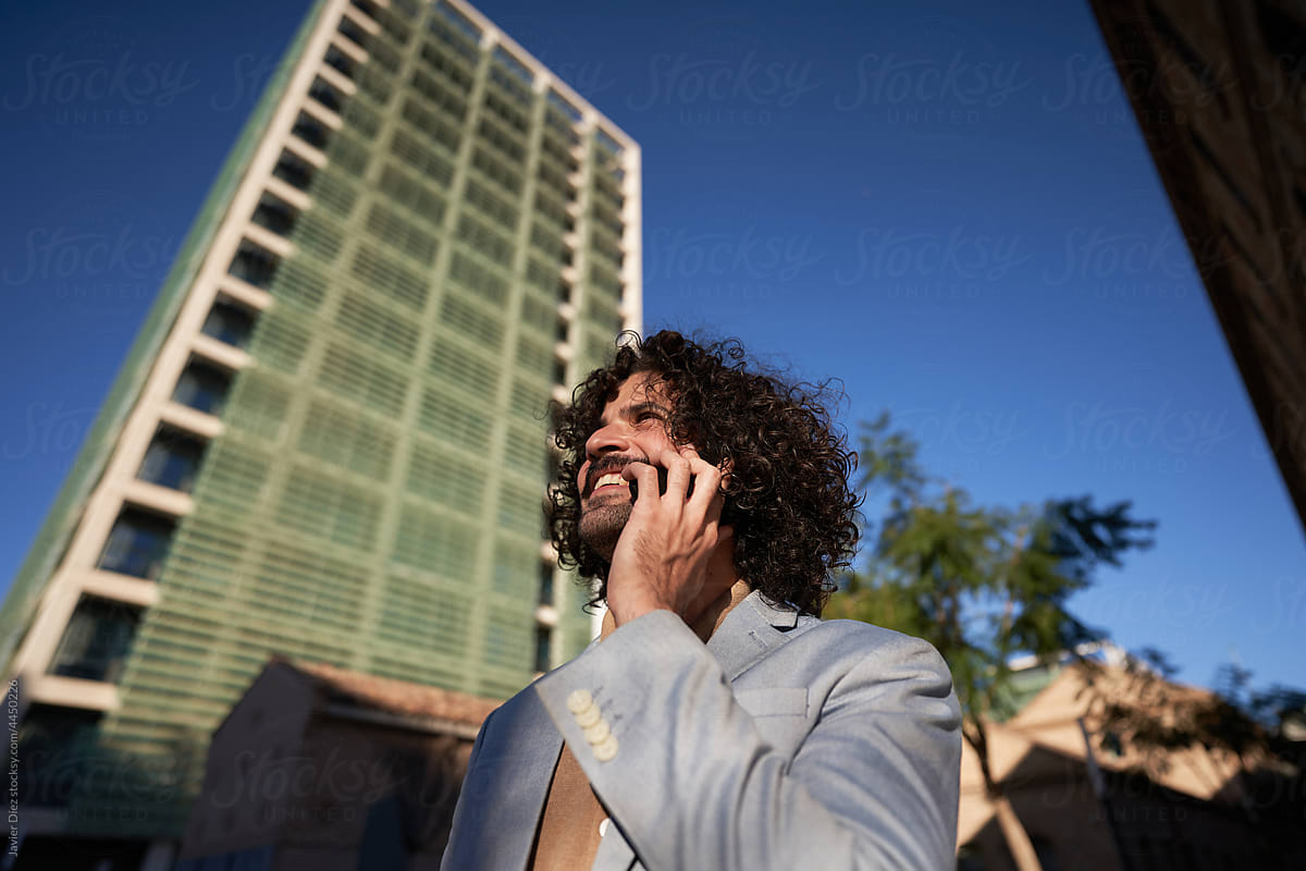 Cheerful businessman speaking on smartphone on street