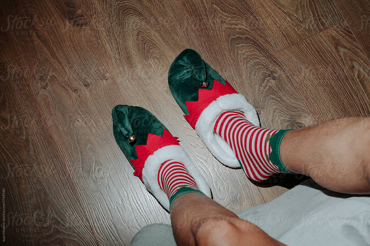 man sitting on bed wearing elf shoes