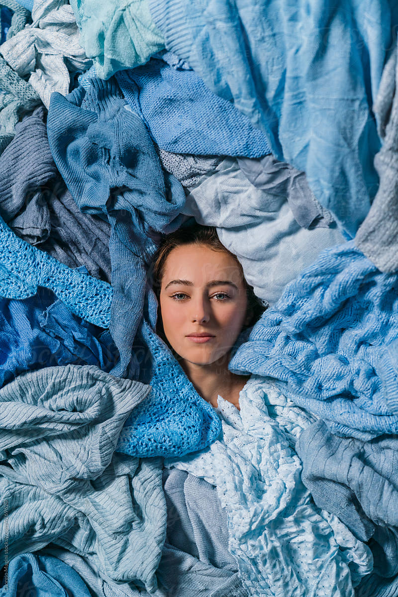 Woman Surrounded by Blue Used Clothes for Recycling