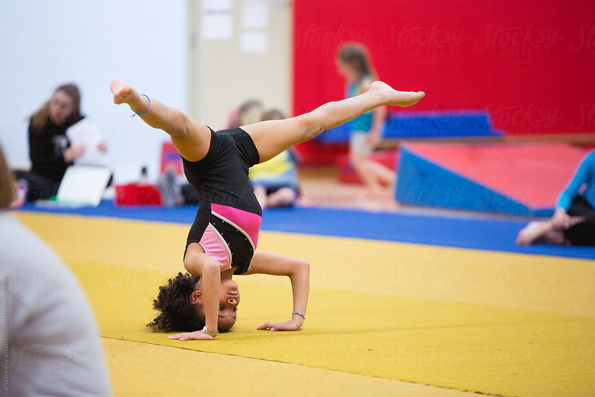 A child balancing on her head at gymnastics