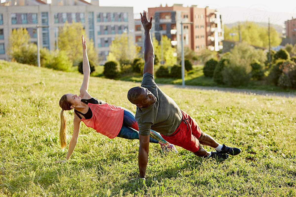 Determined Athletes Doing Side Plank Pose In Park