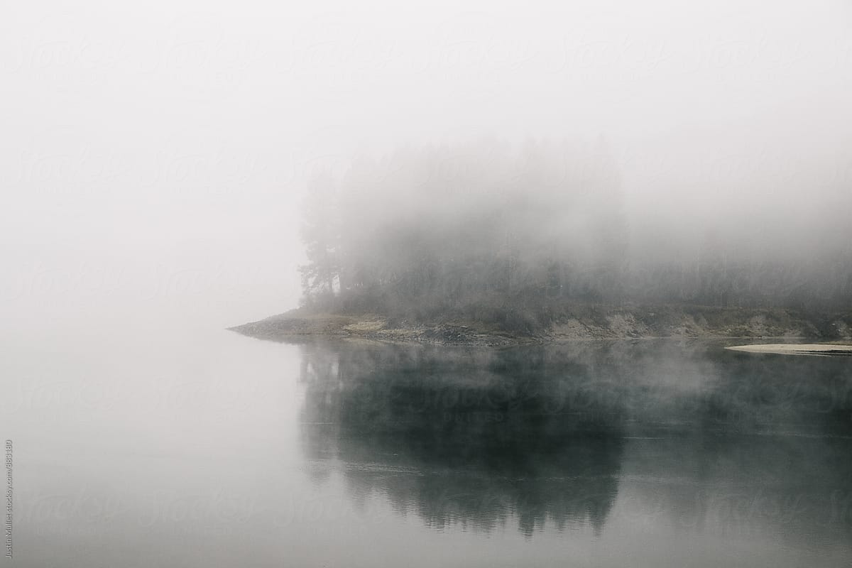 An island on a river nearly hidden by thick fog