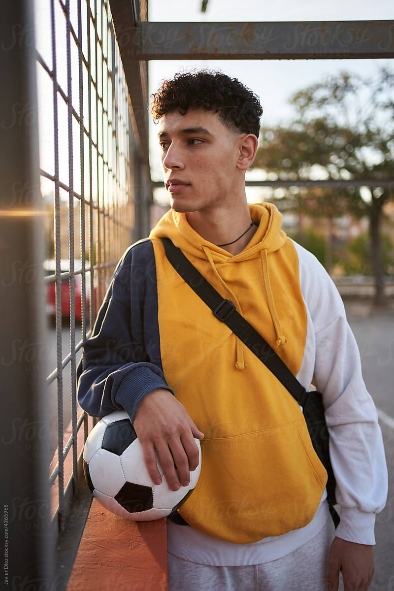 Serious man with soccer ball looking through grid