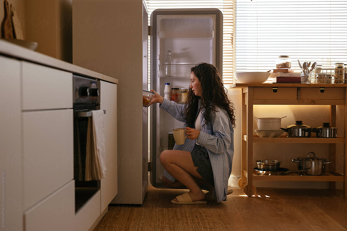 Teen girl looks into refrigerator for healthy snack