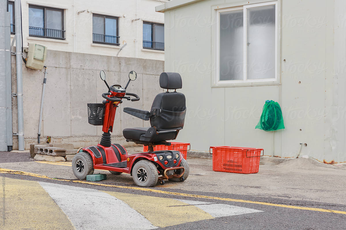 Red mobility scooter parked next to a house.