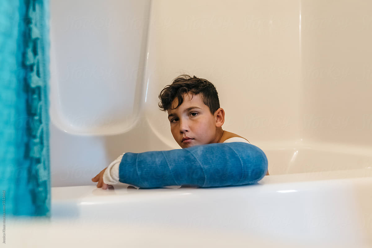 Boy with arm cast taking bath.