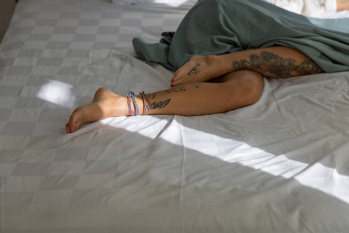 A Faceless Woman With Tattoos Relaxes In Bed