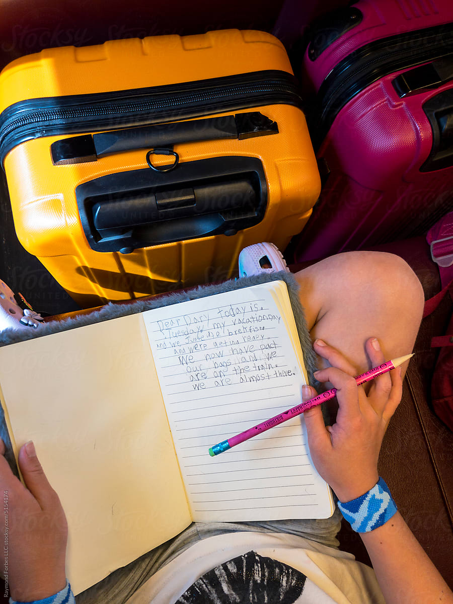 Young Girl hand Writing in travel diary journal on train UGC